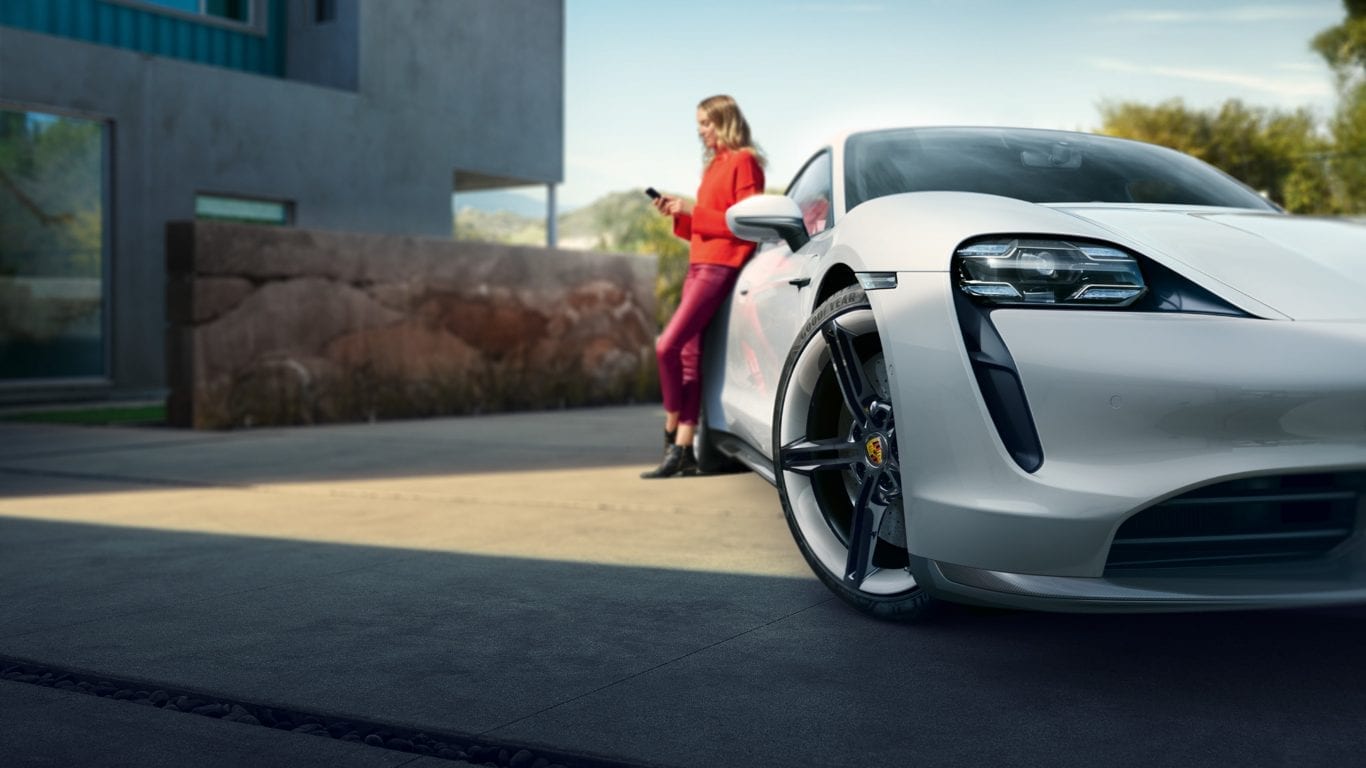Nainen nojaa valkoiseen Porscheen