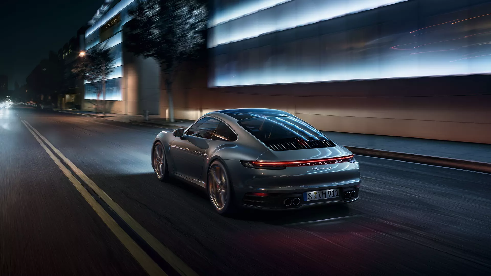 Harmaa Porsche 911 ajamassa yöllä tiellä kaupungissa.