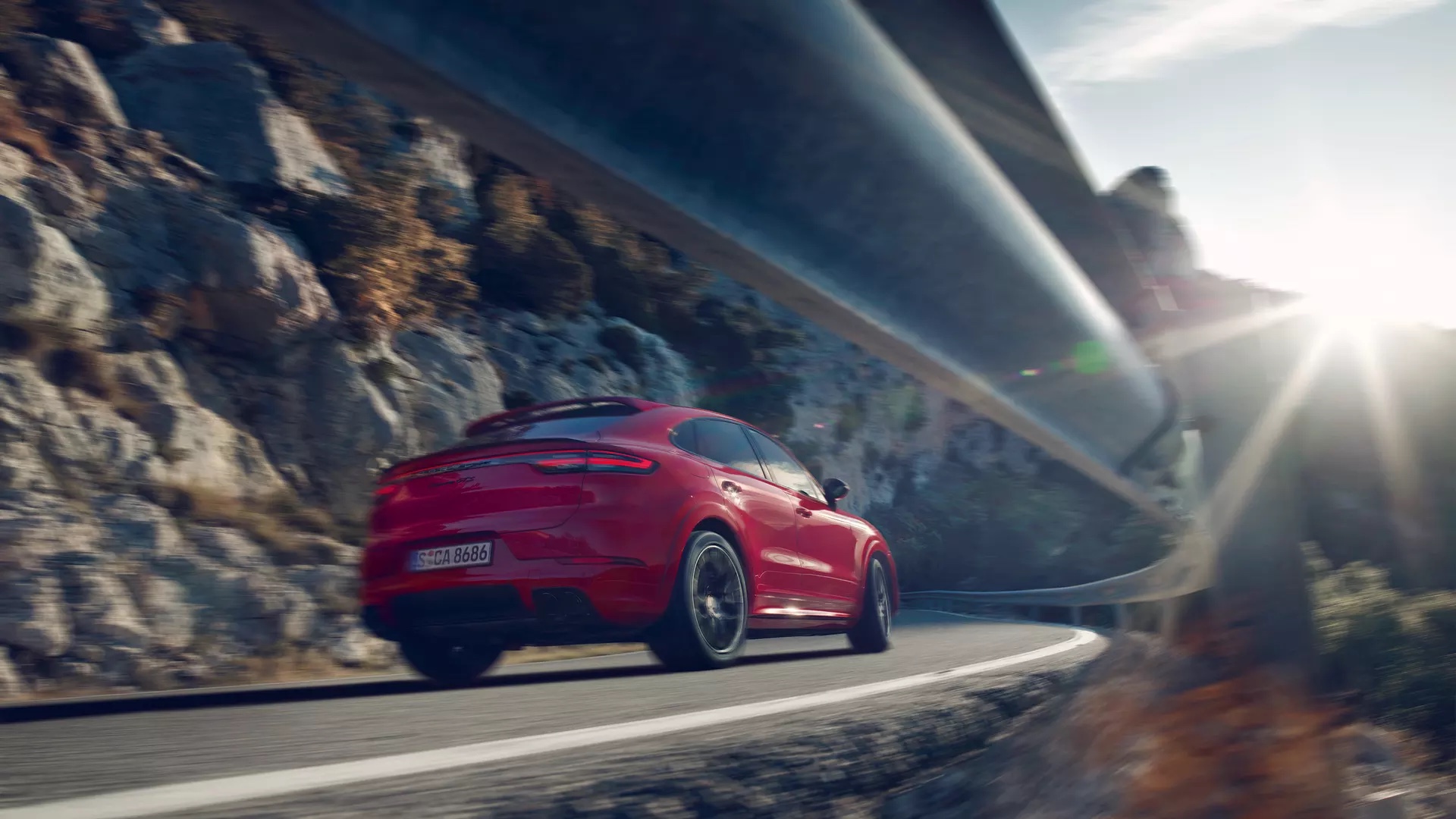 Punainen Porsche Cayenne vuoristotiellä.