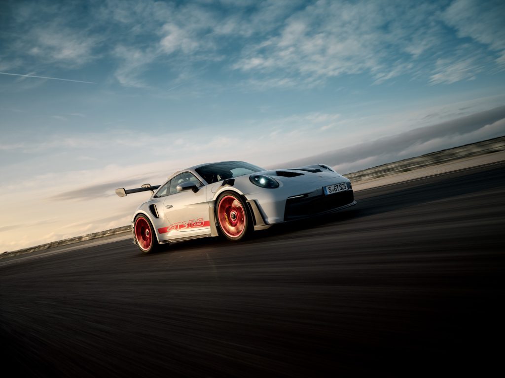 Harmaa Porsche 911 GT3 RS punaisilla vanteilla ajamassa radalla.