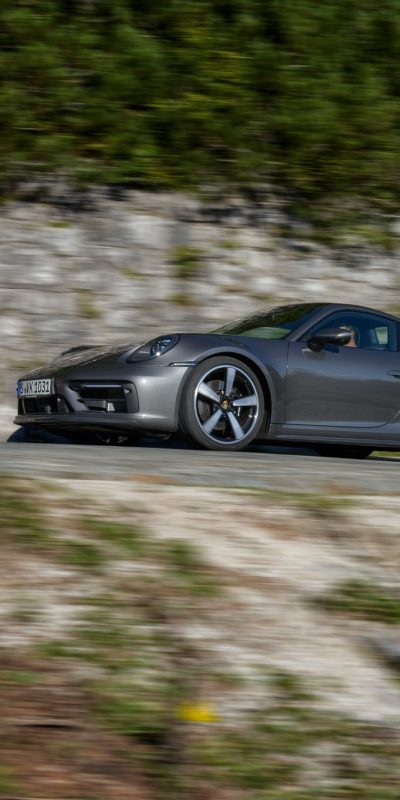 Harmaa Porsche 911 maantiellä kesäisissä maisemissa