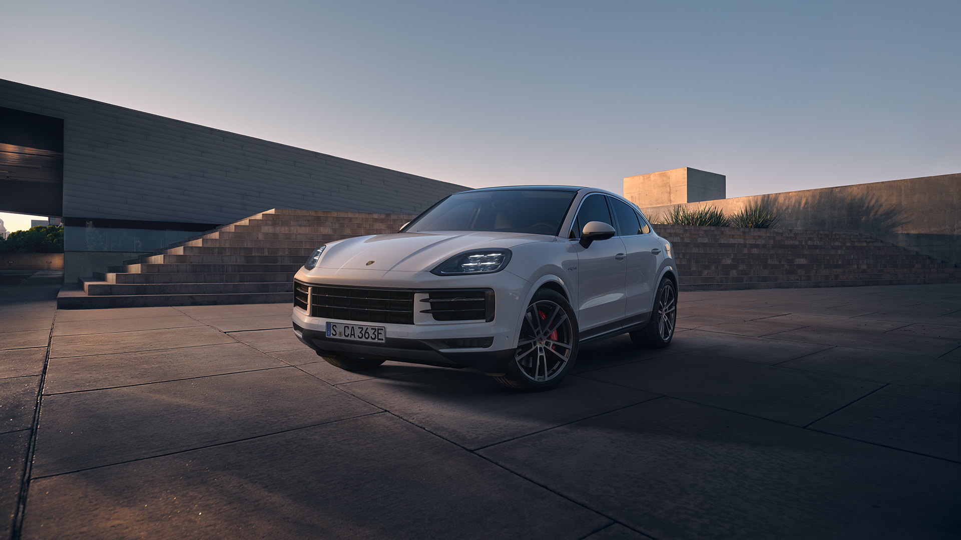 Valkoinen Porsche Cayenne e-Hybrid parkissa asfalttisella pihalla.
