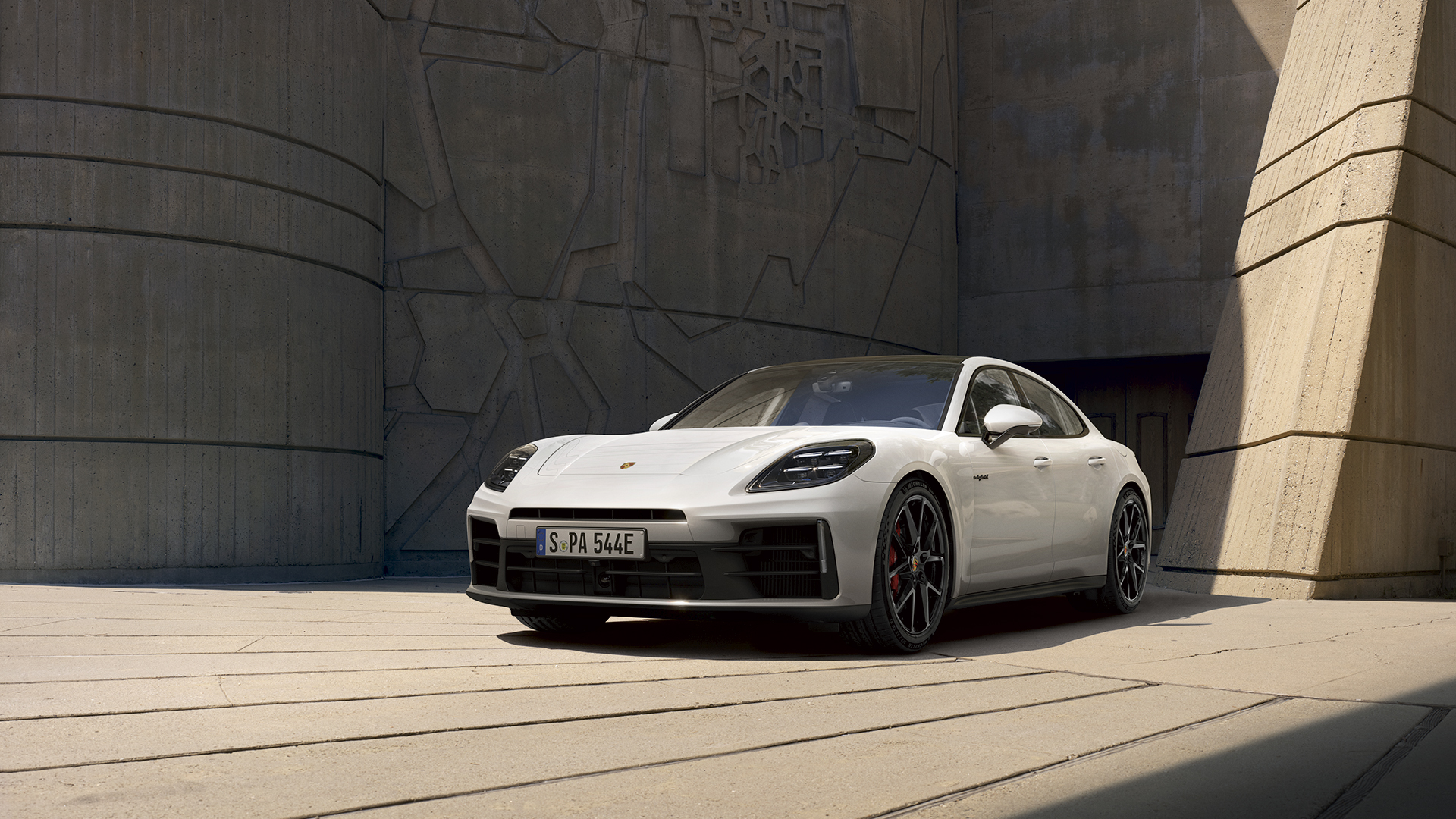 Valkoinen Porsche Panamera e-Hybrid parkissa kivirakennuksen edessä.