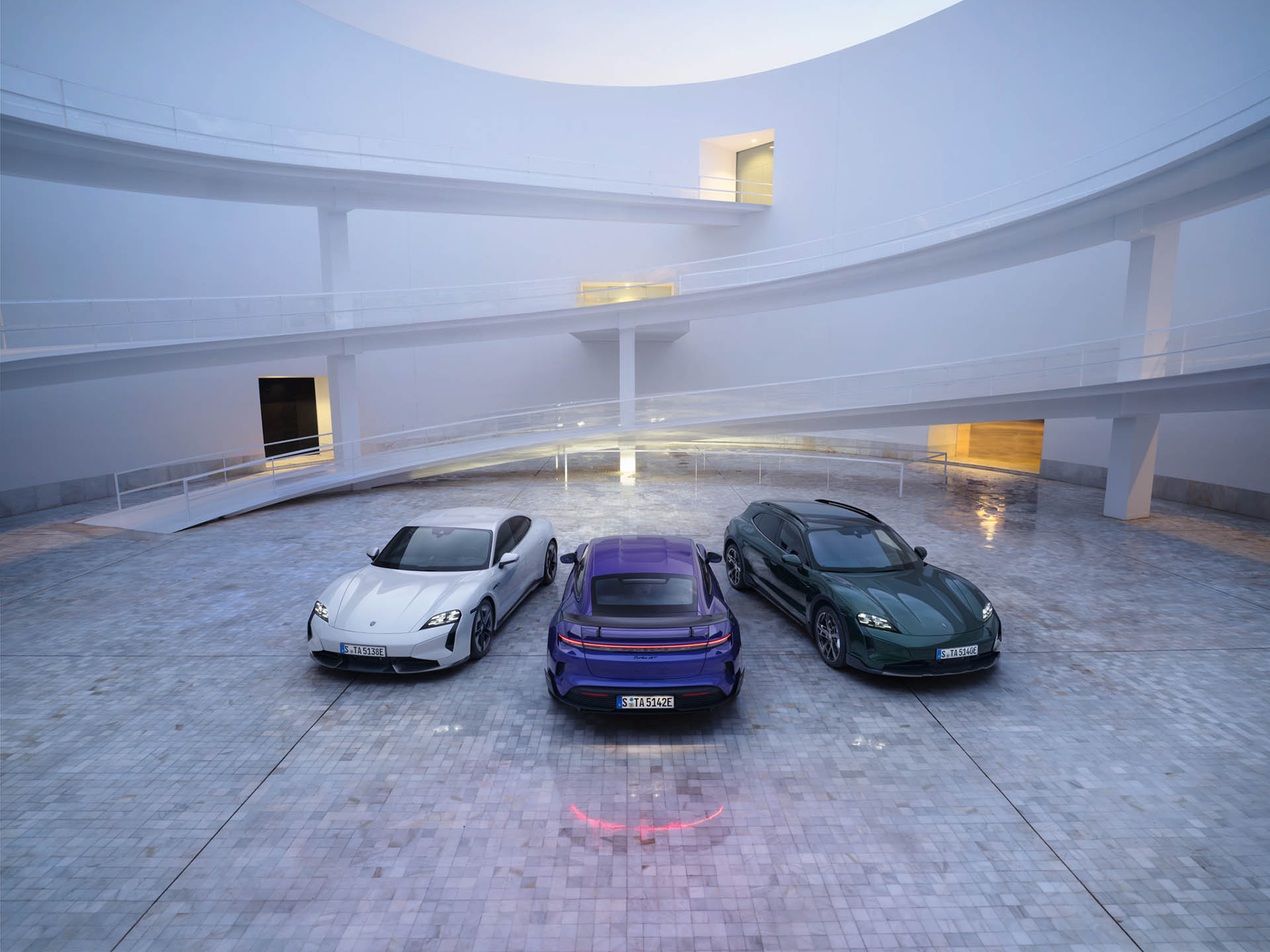 Kolme Porschea parkkeerattuna valkoisessa rakennuksessa.